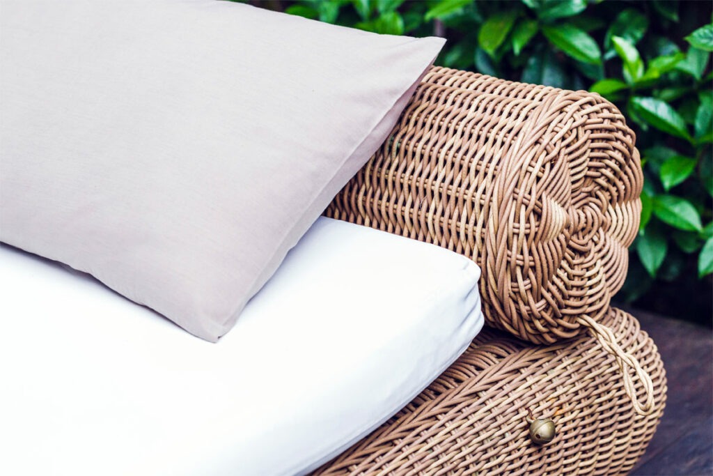 Rattan-Couch mit Kissen steht im Garten